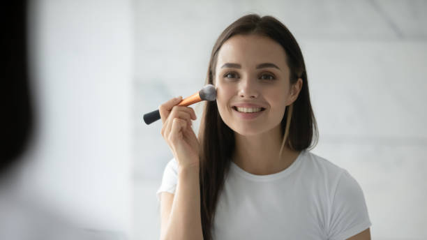 istock Close up head shot smiling woman applying blush on cheeks 1271917135