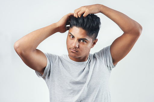 Studio shot of a young man putting his fingers through his hair