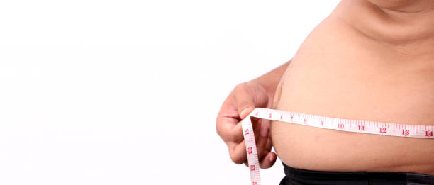 istock Fat man hand holding excessive belly fat with measuring tape on white background in studio With copy space. 1271925041