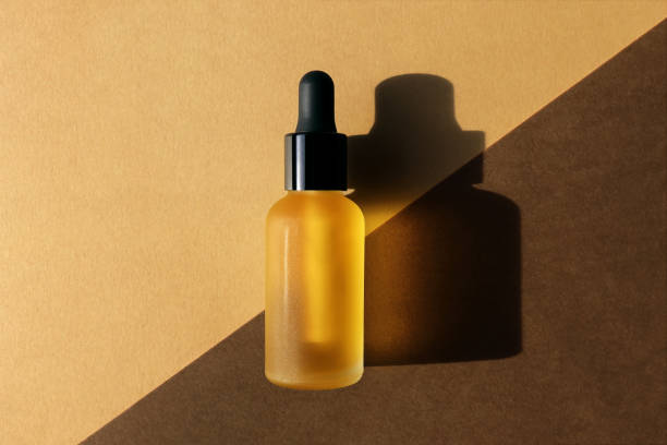 Dropper oil bottle on diagonal background, flat lay. Monochrome brown mockup