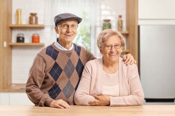 istock Elderly couple standing in a kitchen behind a wooden table 1271925232