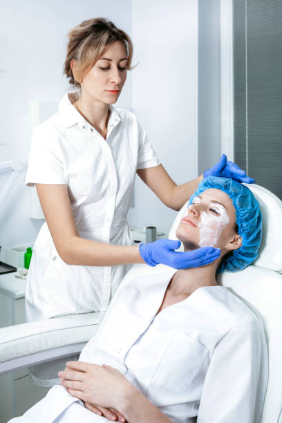 istock Cosmetologist is applying cream with anesthesia on patient's face. Preparing skin for biorevitalization procedure 1271927621