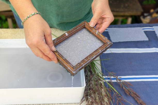 istock Woman holding frame for making paper sheets from waste paper pulp. Selective focus. Decorative and applied art. Recycling concept, ecology. 1271929437