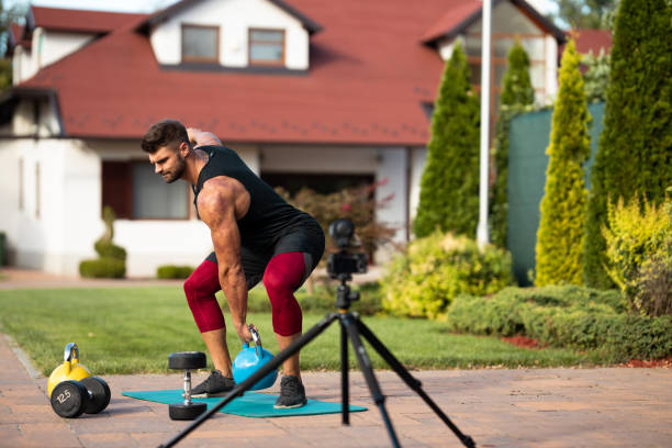 istock Male athlete doing exercise in backyard and filming vlog. 1271931975
