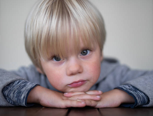 istock A young boy pose in front of a white screen with his hands on his hands leaning on a table. 1271933514