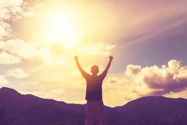 Copy space of man hand raising on top of mountain and sunset sky abstract background. Freedom travel adventure and business victory concept. Vintage tone filter effect color style.