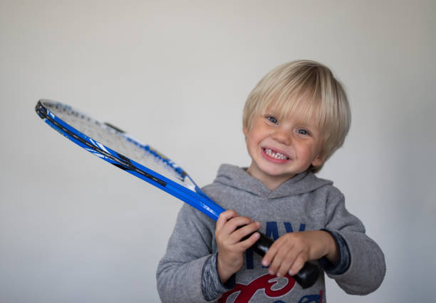istock A young boy pose in front of a white screen with an old tennis racket 1271934072