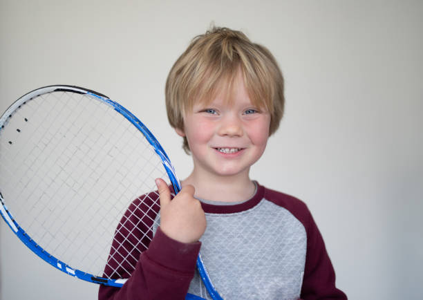 istock A young boy pose in front of a white screen with an old tennis racket 1271935277