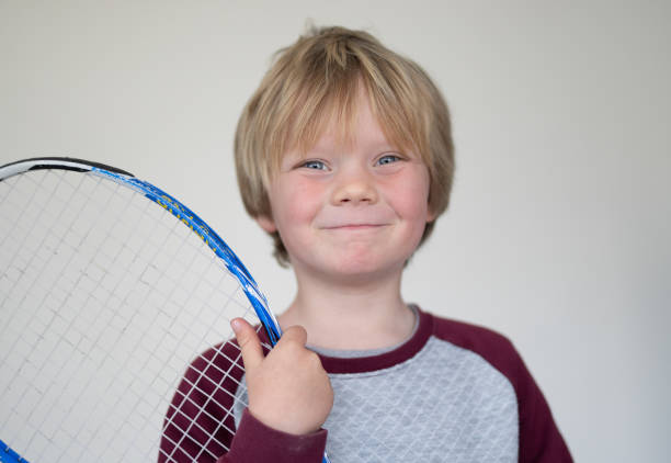 istock A young boy pose in front of a white screen with an old tennis racket 1271935324