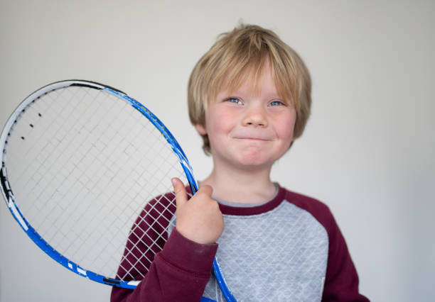 istock A young boy pose in front of a white screen with an old tennis racket 1271935350