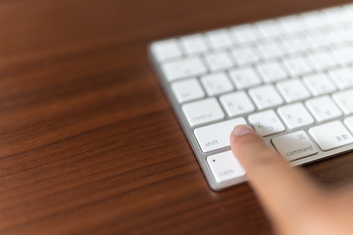 Finger pressing the shift key on the computer keyboard