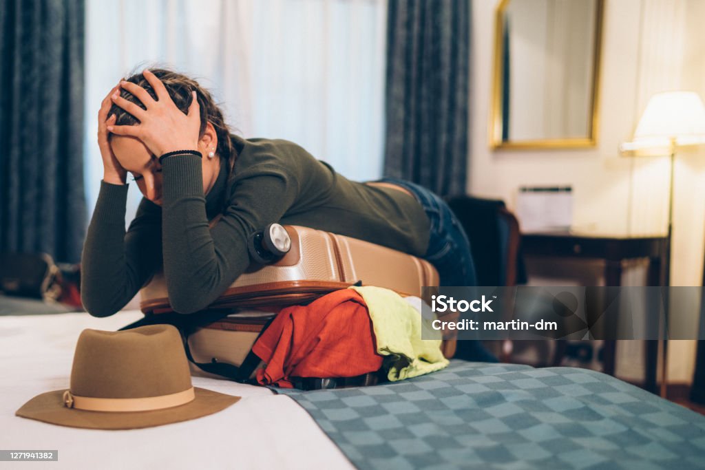 Mujer preocupada por el desbordamiento de la maleta antes de viajar - Foto de stock de Maleta libre de derechos