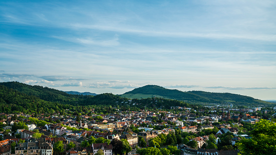Germany, Freiburg im Breisgau, Houses, Churches and skyline between green mountains and trees, aerial view above the city