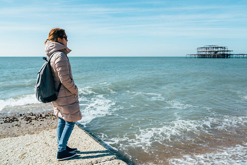 Tourist woman in Brighton staring the sea from the quay