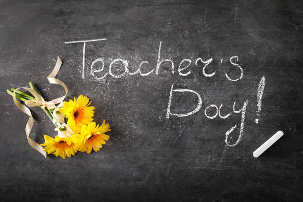istock Teacher's day greeting card on black chalkboard background. Top view. 1271943429