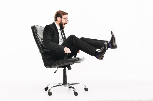 Photo of young excited businessman sitting isolated over white background. Looking aside.