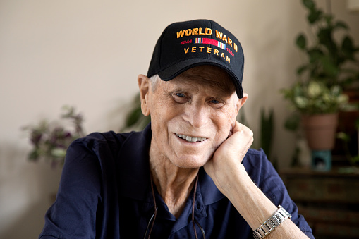 Cabeza sonriente veterano de la Segunda Guerra Mundial descansando a mano mirando a la cámara photo