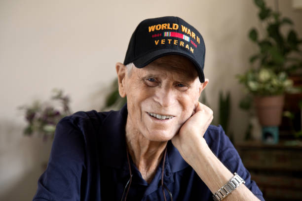 World War Two Veteran smiling head resting on hand looking at camera Elderly veteran sitting at home in a pleasant mood. veteran stock pictures, royalty-free photos & images