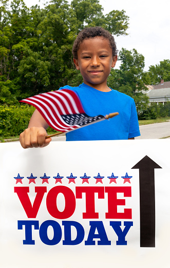 Little Boy encouraging Voters Waving an American Flag