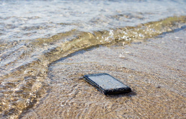 verloren smartphone onder water op zee. het verliezen van telefoon het strand, conceptbeeld. - lost phone stockfoto's en -beelden