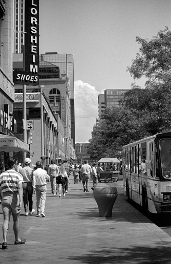 Denver, Colorado, U.S.A . - June 11, 1990: Looking towards the Colorado State Capitol building, people walk the downtown 16th Street Mall sidewalk lined with skyscrapers, shops and businesses as busses roll by.