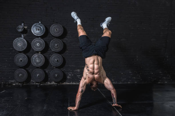 jovem homem musculoso forte em forma fazendo mão stand e andar na academia como hardcore cross treino - parada de mãos - fotografias e filmes do acervo