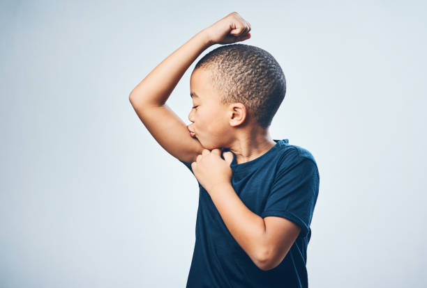 A future bodybuilder in the making Studio shot of a cute little boy kissing his muscles against a grey background flexing muscles stock pictures, royalty-free photos & images