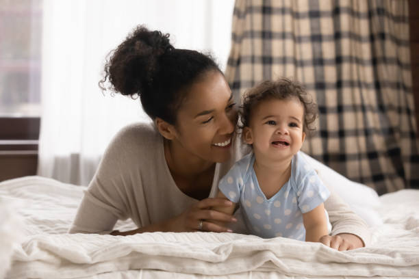 istock Affectionate mixed race woman lying on bed with cute baby. 1271954630