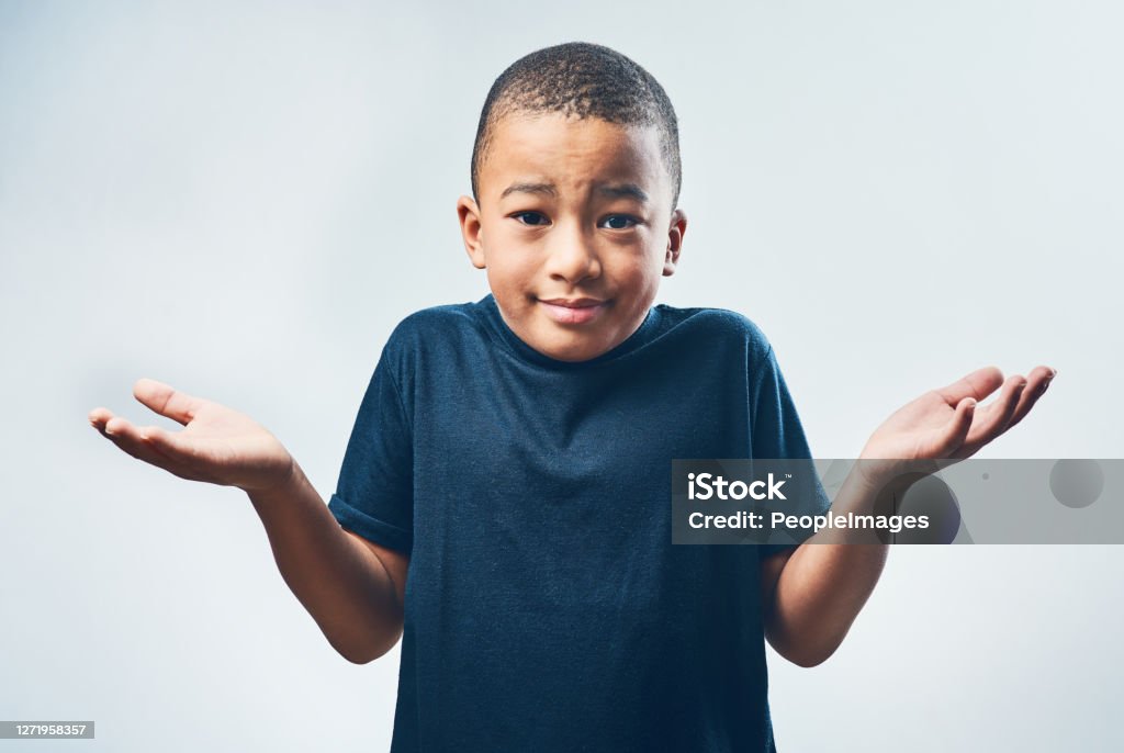 I don't get it Studio shot of a cute little boy shrugging his shoulders against a grey background Child Stock Photo