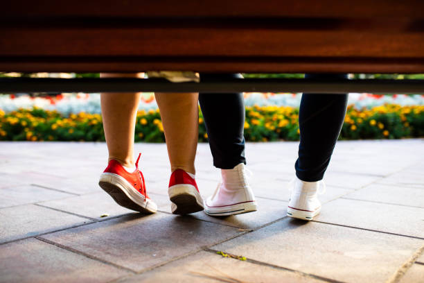 istock Legs of a couple underneath a park bench 1271959424