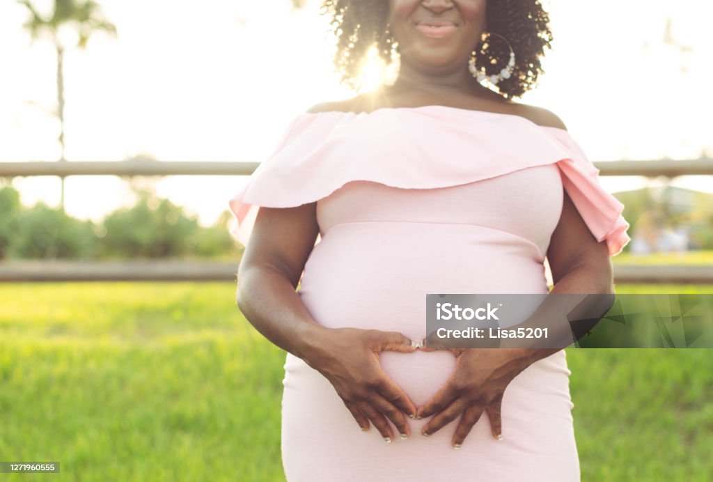 close up of African American woman making heart hands on pregnant belly Close up of African American woman making heart hands, the shape of a heart, around her pregnant belly Pregnant Stock Photo
