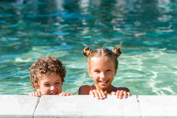 istock girl looking at camera while spending time in swimming pool with curly boy 1271964160