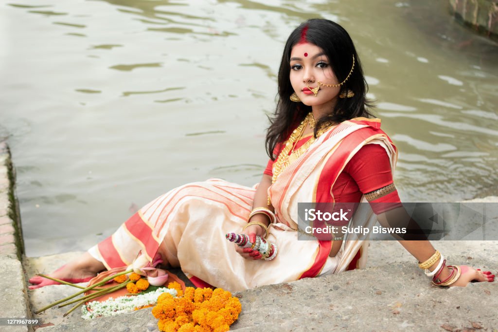 Portrait Of Beautiful Indian Girl In Front Of Ganga River Wearing  Traditional Indian Saree Gold Jewellery And Bangles Holding Plate Of  Religious Offering Maa Durga Agomoni Shoot Concept Stock Photo - Download