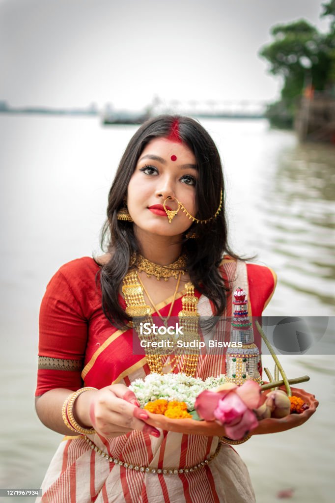Portrait Of Beautiful Indian Girl Standing In Front Of Ganga River Wearing  Traditional Indian Saree Gold Jewellery And Bangles Holding Plate Of  Religious Offering Maa Durga Agomoni Shoot Concept Stock Photo -