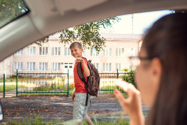 istock Little boy elementary school learner going to school, waving goodbye to his mother who is sitting in the car. 1271969850