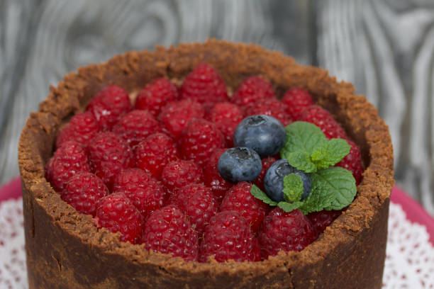 istock No-bake chocolate cake with cream cheese. Garnished with raspberries, blueberries and mint leaves. On the surface of pine boards painted in black and white. 1271970683