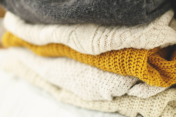 istock Cozy knitted sweater stack for cold autumn weather on white background. Stylish white, yellow and grey sweaters close up with space for text. Hello fall! 1271972186