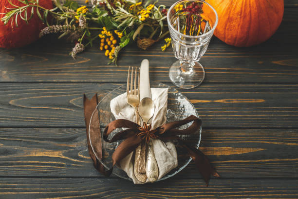 istock Thanksgiving dinner table setting. Stylish plate with cutlery and autumn decorations, pumpkin, natural branches and autumnal flowers on rustic table. Autumn wedding catering 1271972903