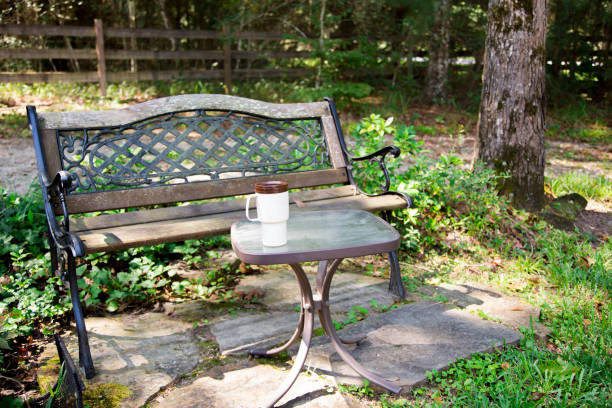公園のテーブルの上に単一の再利用可能なコーヒーマグカップ。 バックグラウンドでベンチ。 - texas tea ストックフォトと画像