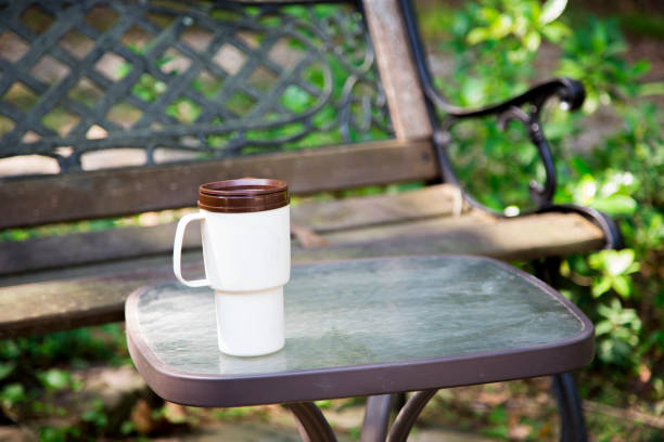 taza de café reutilizable en la mesa en el parque.  banco de fondo. - texas tea fotografías e imágenes de stock