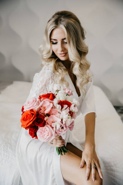 elegant blonde bride dressed in white holding a wedding bouquet