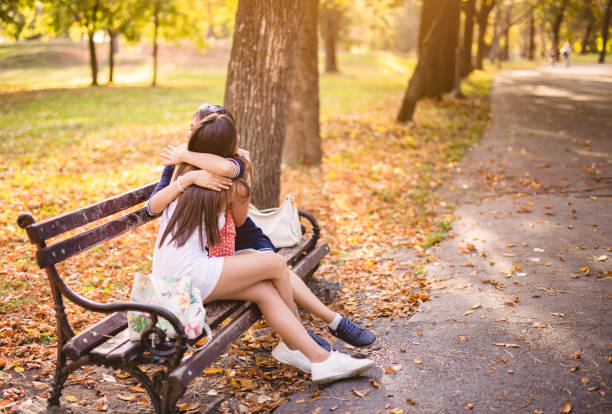 istock Two young woman embracing on bench 1271975845