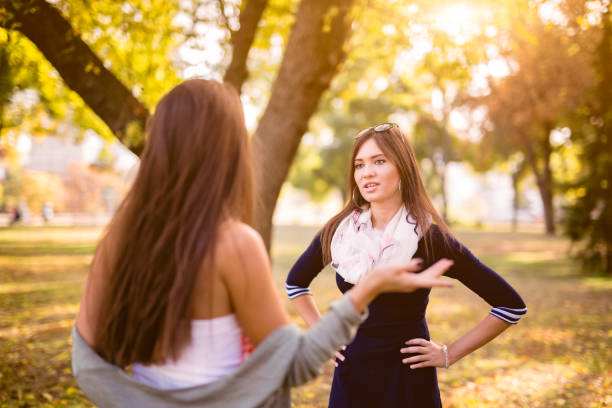 Women arguing in a public park Two young Caucasian women arguing in a public park. sister stock pictures, royalty-free photos & images