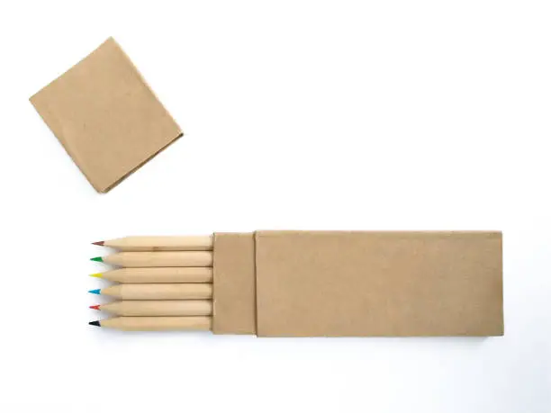Photo of Aerial view of wooden pencils with colored tips in horizontal position and recycled paper case isolated on white. Crayons with eco-friendly cover. School supplies and back to school pattern.