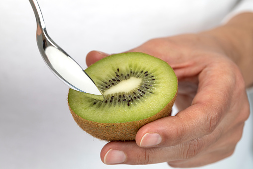 Close-up of a person eating a kiwi with a spoon.