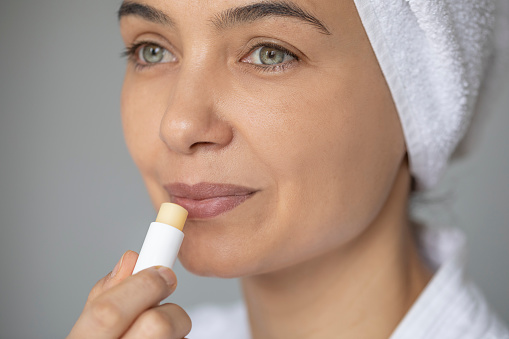 Beautiful woman applying lip protector on her lips.