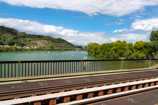 Tracks on the railway bridge over the river, visible railings, ships and blue sky with clouds in the background.