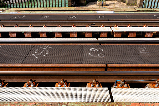 Tracks on the railway bridge over the river, visible fixing screws and metal sleepers.