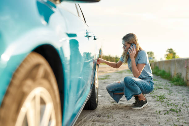 Attractive young woman looking sad, calling car service, assistance or tow truck while having troubles with her auto, checking wheel after car breakdown on local road side Attractive young woman looking sad, calling car service, assistance or tow truck while having troubles with her auto, checking wheel after car breakdown on local road side, Horizontal shot tow truck stock pictures, royalty-free photos & images