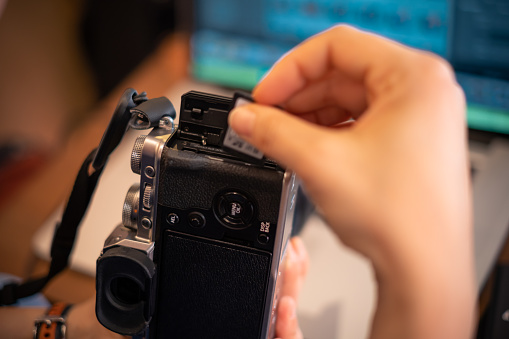 Female hand inserting memory card to camera